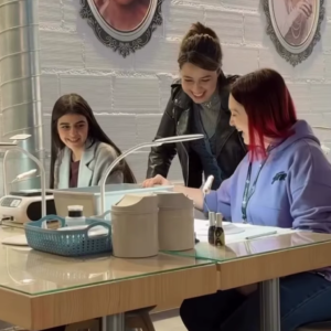 Formadora corrigiendo a una alumna durante una práctica de uñas